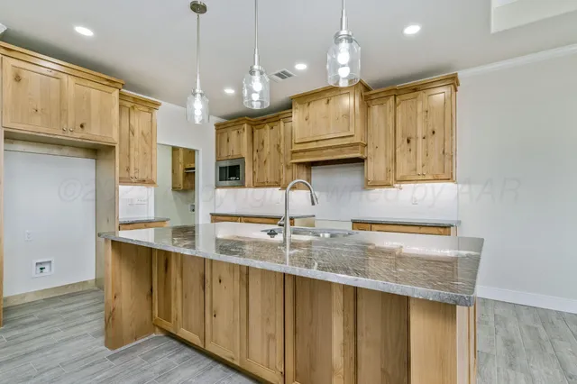 a kitchen with kitchen island granite countertop a sink a center island and cabinets