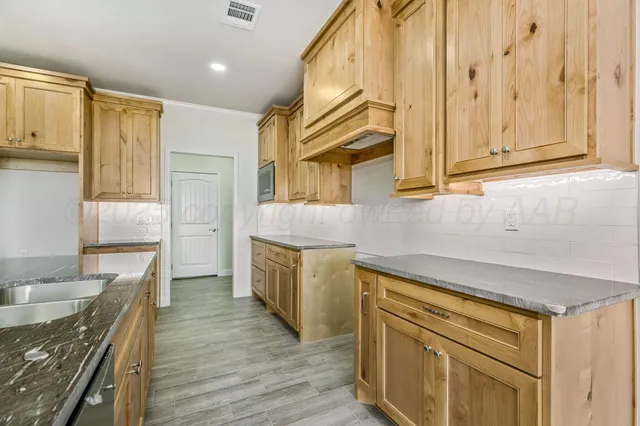 a kitchen with stainless steel appliances granite countertop a sink a stove cabinets and wooden floor