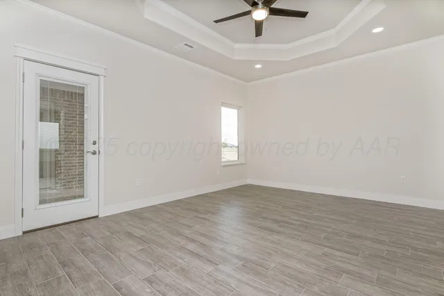 an empty room with wooden floor fan and windows