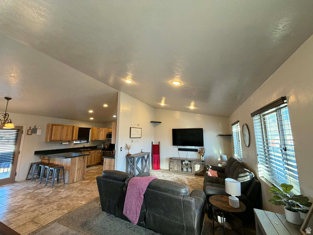 2095 West 4100 North Spring Glen, UT 84526 - Photo 2 of 35 Living area with healthy amount of natural light, light stone finish floors, and vaulted ceiling