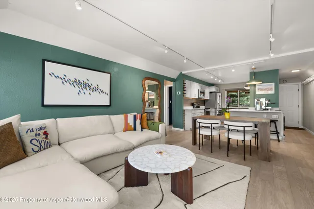a living room with furniture a table and kitchen view