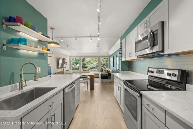 a kitchen with stainless steel appliances granite countertop a sink a stove and a refrigerator