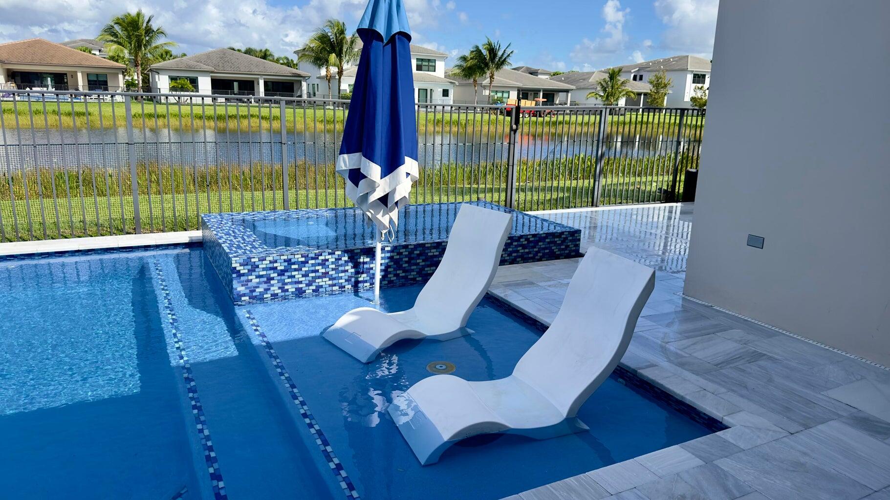 8817 New River Falls Road Boca Raton, FL 33496 - Photo 36 of 54 a view of a deck with couches table and chairs under an umbrella with wooden floor