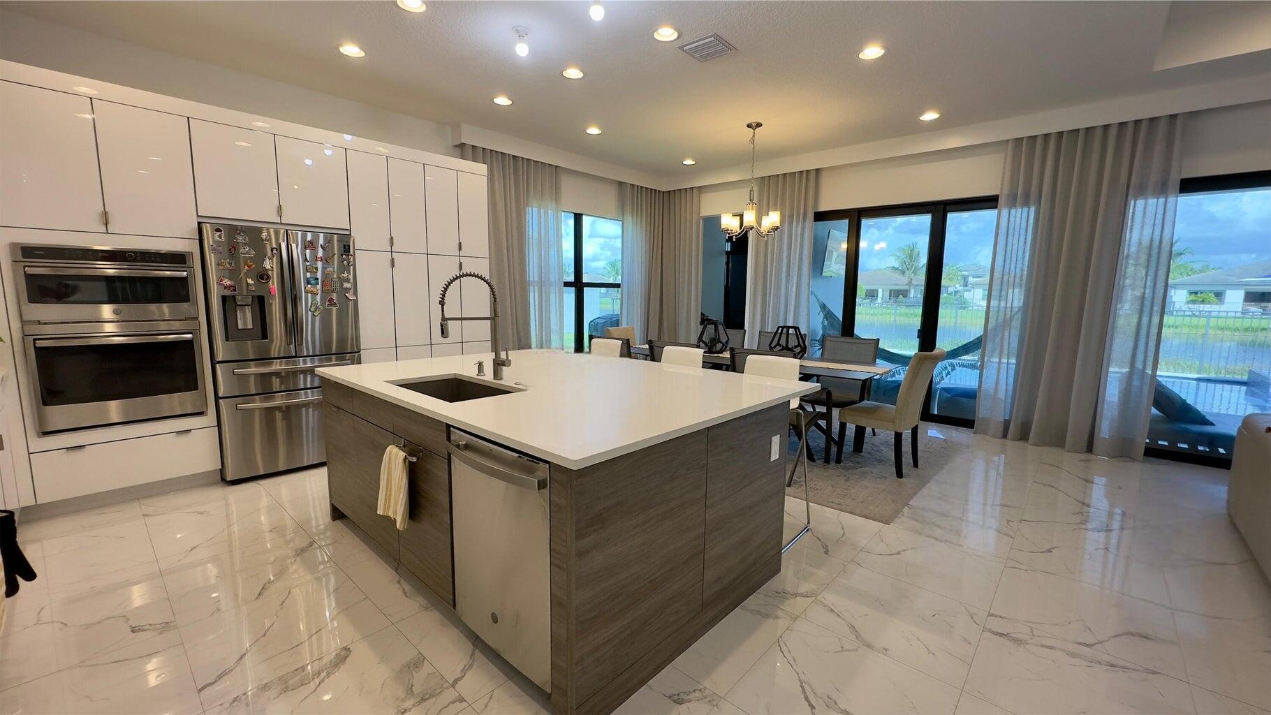8817 New River Falls Road Boca Raton, FL 33496 - Photo 8 of 54 a kitchen with stainless steel appliances a table and chairs