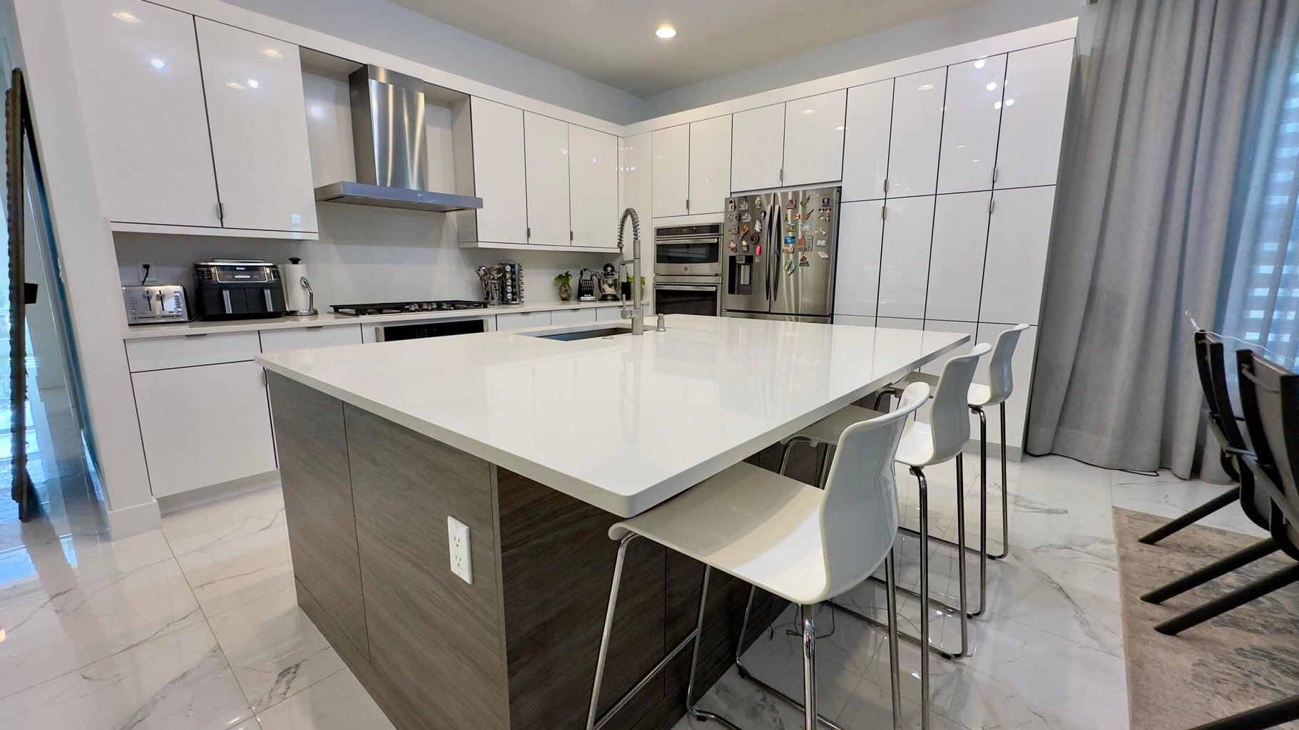 8817 New River Falls Road Boca Raton, FL 33496 - Photo 10 of 54 a kitchen with kitchen island white cabinets and stainless steel appliances