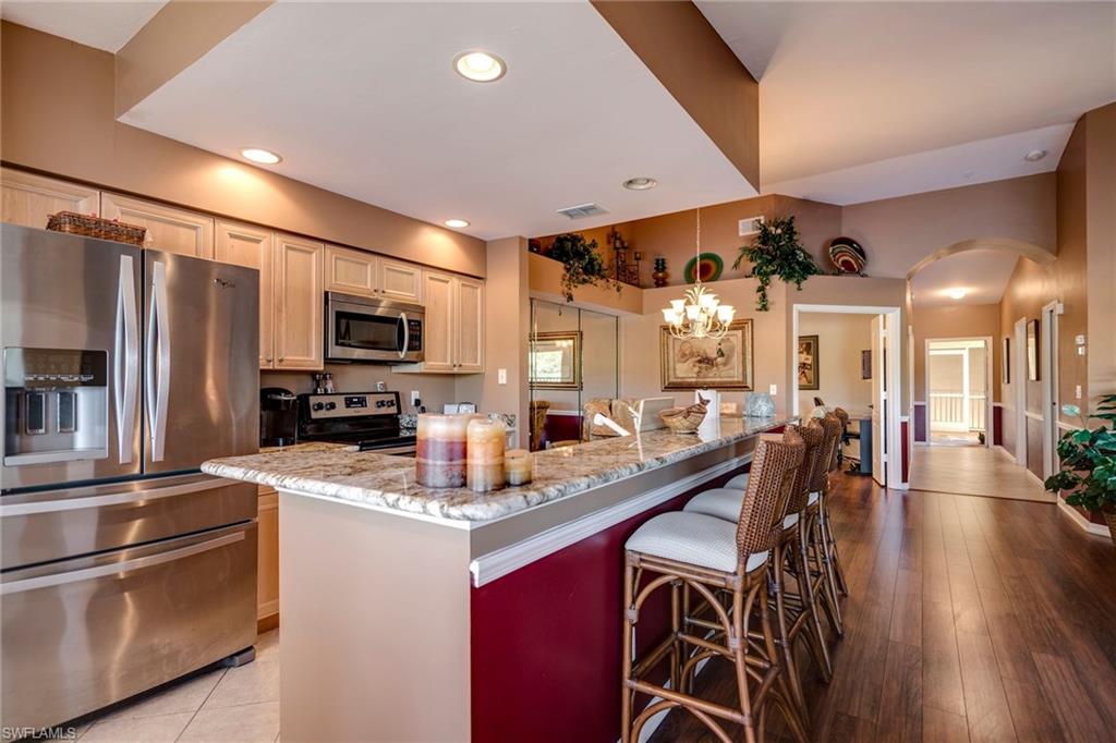 7635 Arbor Lake Court, Unit 2423 Naples, FL 34112 - Photo 11 of 35 a kitchen with stainless steel appliances granite countertop a stove refrigerator and chairs