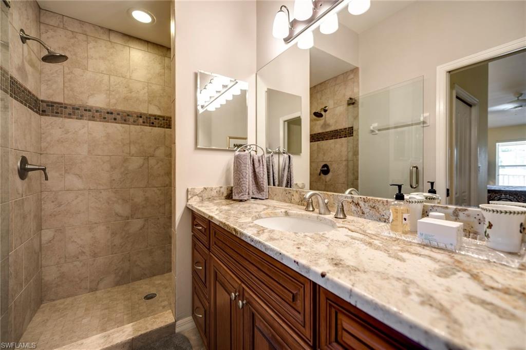 7635 Arbor Lake Court, Unit 2423 Naples, FL 34112 - Photo 17 of 35 a bathroom with a granite countertop sink mirror and shower