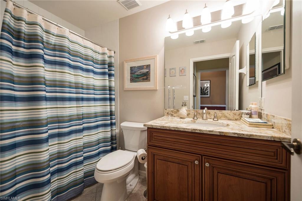 7635 Arbor Lake Court, Unit 2423 Naples, FL 34112 - Photo 19 of 35 a bathroom with a granite countertop toilet sink and mirror