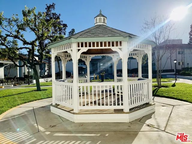 a view of a white house with a small yard and large trees