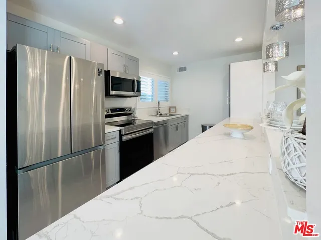 a kitchen with granite countertop a refrigerator and a sink
