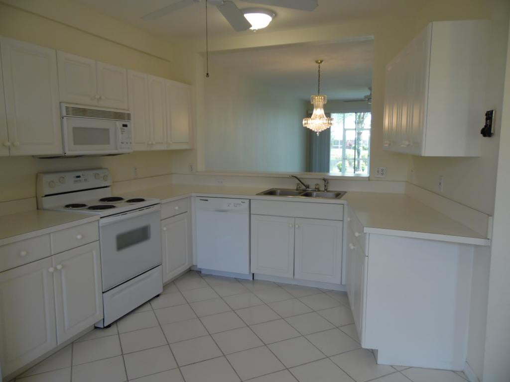9009 Michael Circle, Unit 109 Naples, FL 34113 - Photo 4 of 18 a kitchen with white cabinets appliances and a window
