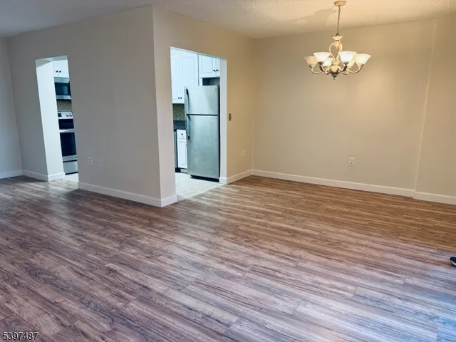 an empty room with wooden floor chandelier and windows