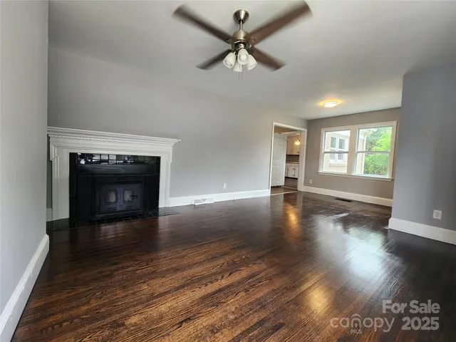 a view of a livingroom with wooden floor a ceiling fan and a fireplace