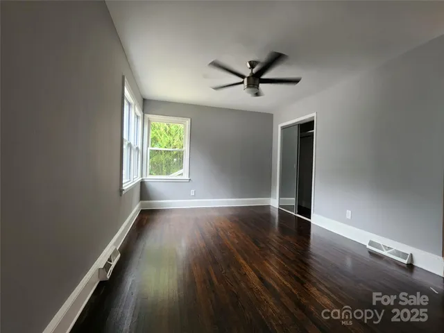a view of empty room with wooden floor and fan