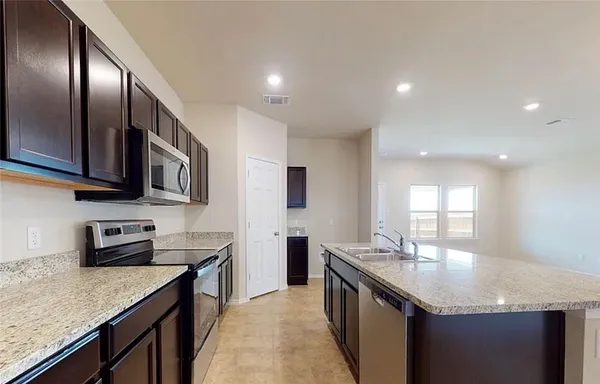 a kitchen with stainless steel appliances granite countertop a sink wooden cabinets and granite counter tops