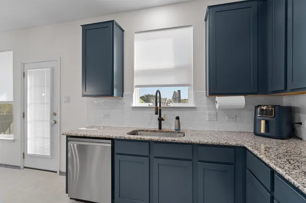a kitchen with granite countertop a sink cabinets and window