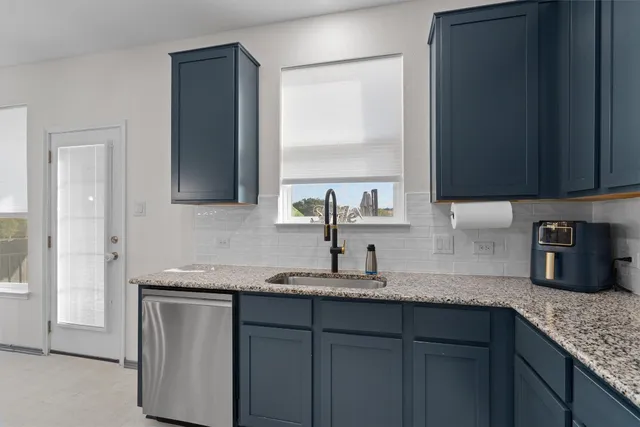 a kitchen with granite countertop a sink cabinets and window