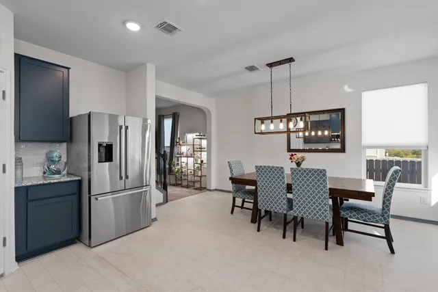 a kitchen with stainless steel appliances refrigerator dining table and chairs