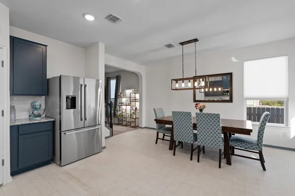 a kitchen with stainless steel appliances refrigerator dining table and chairs