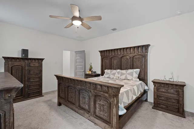a bedroom with a bed a dresser and a chandelier