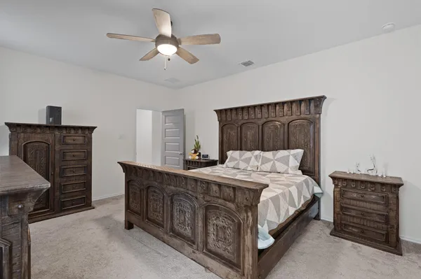 a bedroom with a bed a dresser and a chandelier