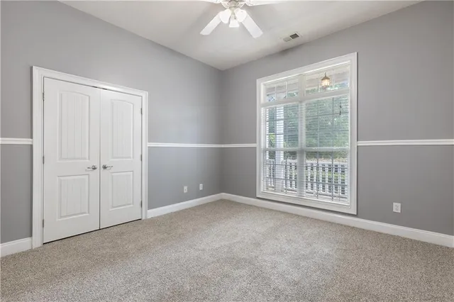 an empty room with chandelier fan and windows