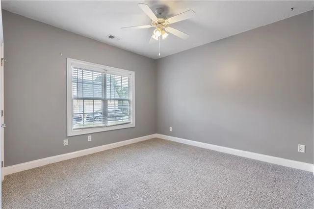 an empty room with a chandelier fan and windows