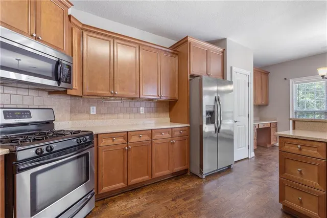 a kitchen with stainless steel appliances granite countertop a refrigerator stove and sink