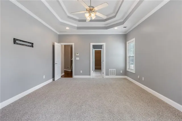 an empty room with chandelier fan and windows