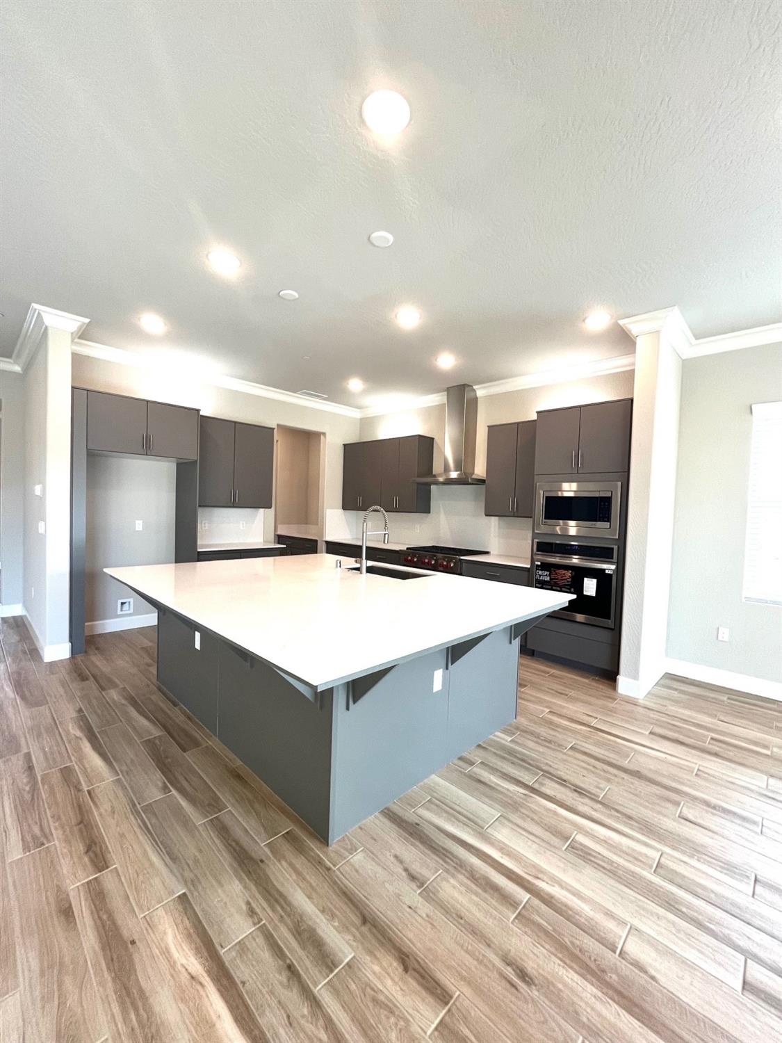 682 Bloom Lane Clovis, CA 93619 - Photo 5 of 30 a large room with kitchen island a sink dishwasher a stove and a refrigerator with wooden floor