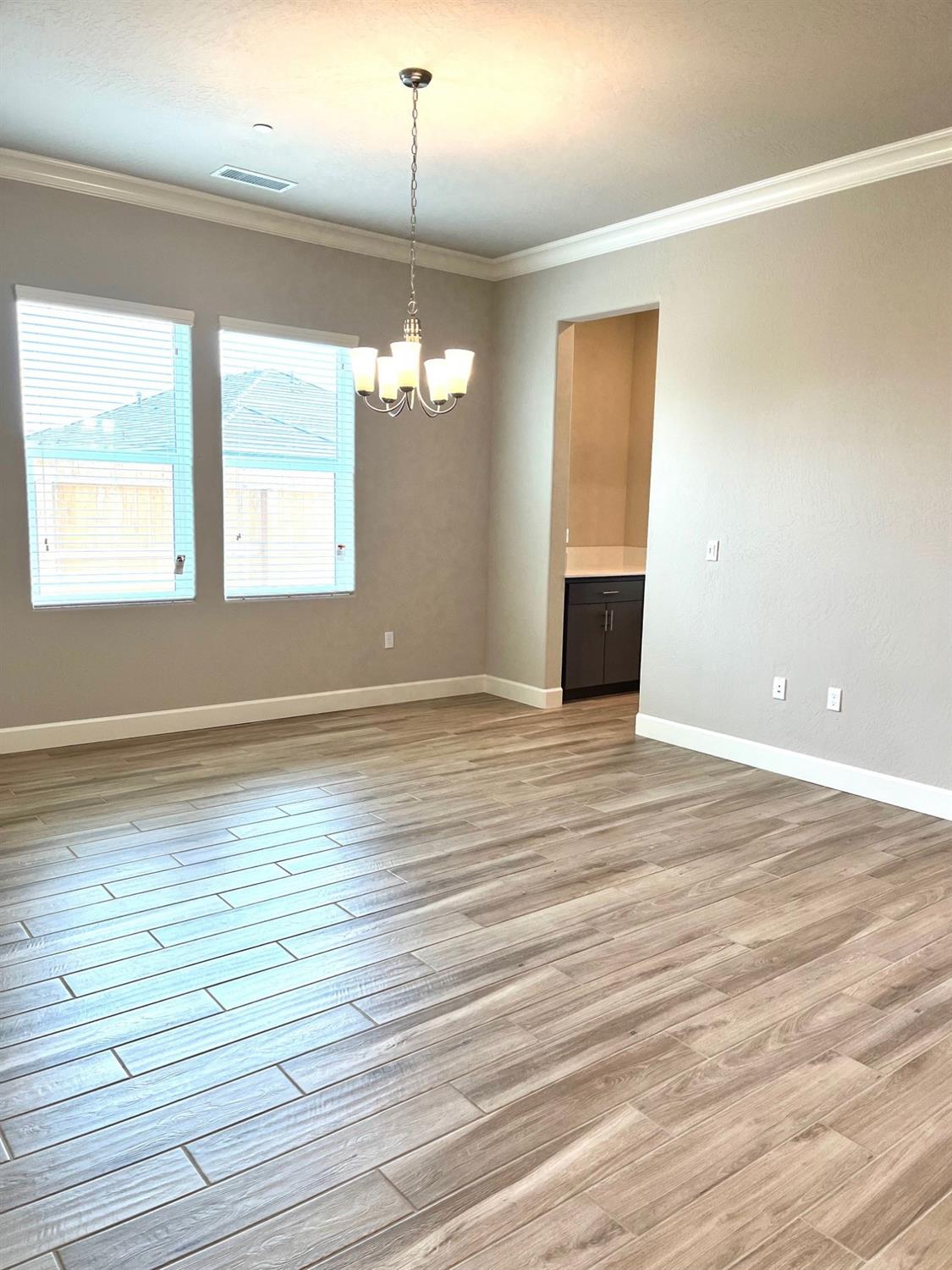 682 Bloom Lane Clovis, CA 93619 - Photo 9 of 30 an empty room with wooden floor chandelier and windows