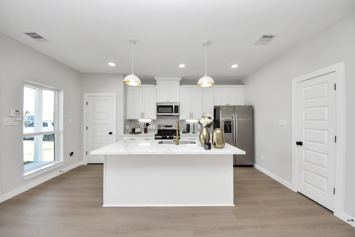 9826 Nedwald Street Houston, TX 77029 - Photo 29 of 50 a large white kitchen with kitchen island a sink a center island stainless steel appliances and a window
