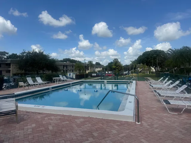 a view of swimming pool with outdoor seating and plants in back