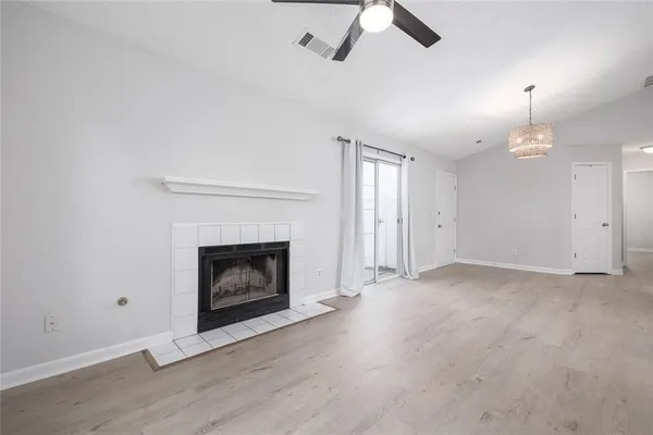 an empty room with ceiling fan fireplace and window