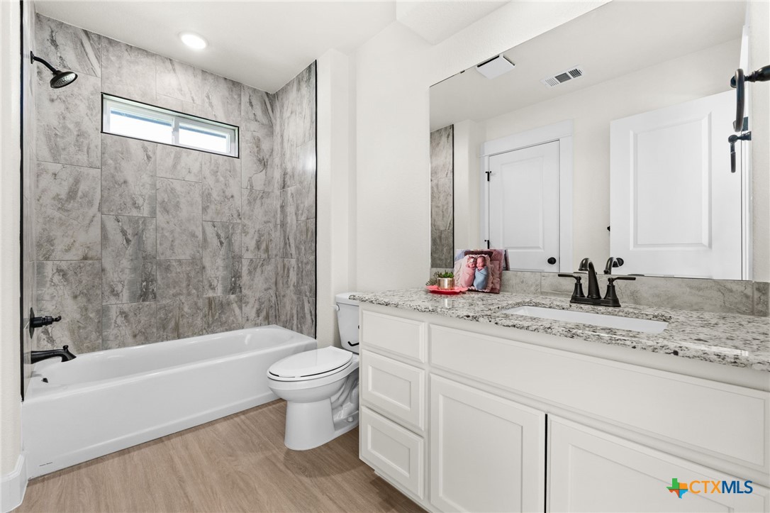 3025 Millhouse Road Copperas Cove, TX 76522 - Photo 23 of 38 a bathroom with a granite countertop sink a toilet and a bathtub