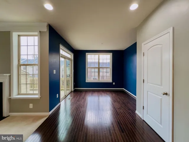 a living room with stainless steel appliances wooden floors and a large window