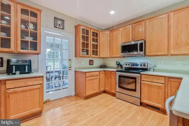 a kitchen with stainless steel appliances granite countertop a stove top oven a sink dishwasher a microwave oven and a refrigerator with wooden cabinets