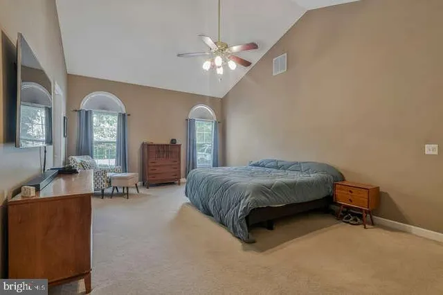 a spacious bedroom with a bed a chandelier and a dresser