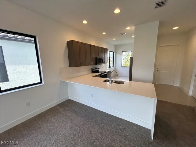 a large white kitchen with sink and a large mirror