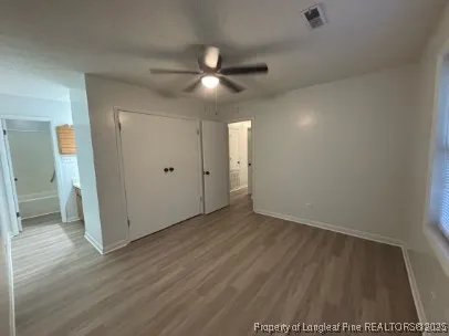 an empty room with wooden floor and a ceiling fan