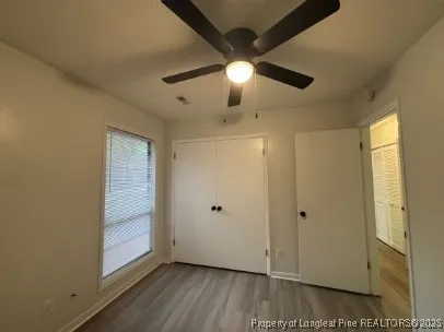 a view of empty room with wooden floor and fan
