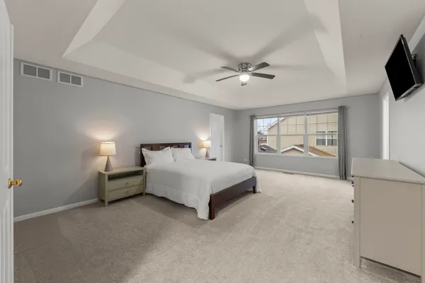a spacious bedroom with a bed and flat screen tv