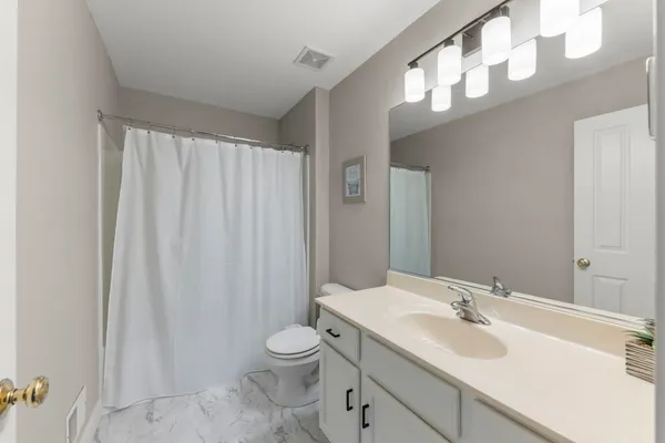 a bathroom with a toilet a sink a mirror a vanity and shower