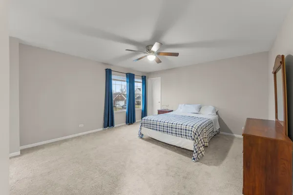 a spacious bedroom with a bed and a ceiling fan