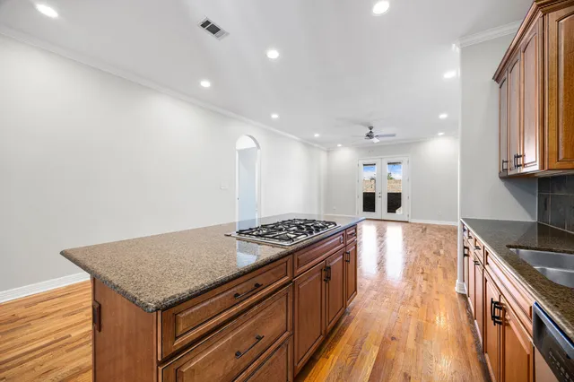 a kitchen with granite countertop kitchen island stainless steel appliances a stove a sink a refrigerator and wooden floor