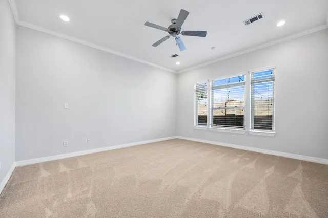an empty room with windows and ceiling fan