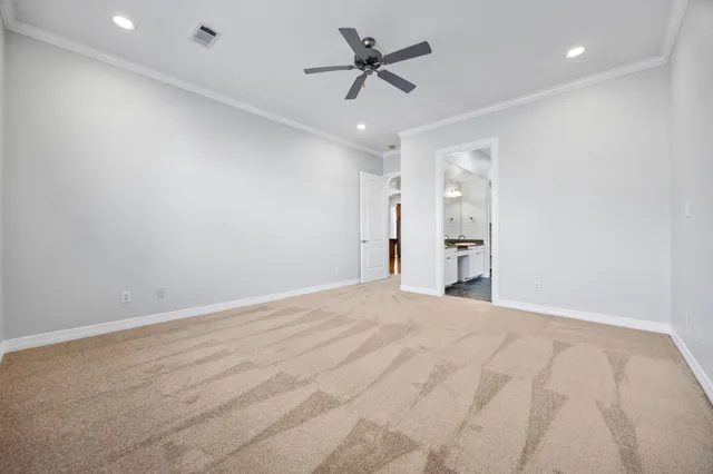 a view of an empty room and a ceiling fan & kitchen view