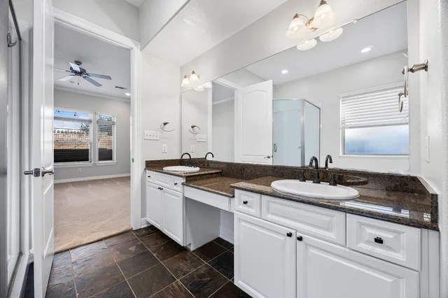a spacious bathroom with a granite countertop sink a mirror and shower