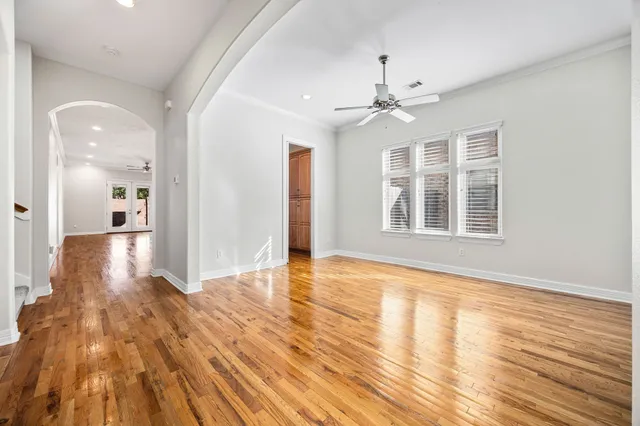 a view of empty room with wooden floor and fan