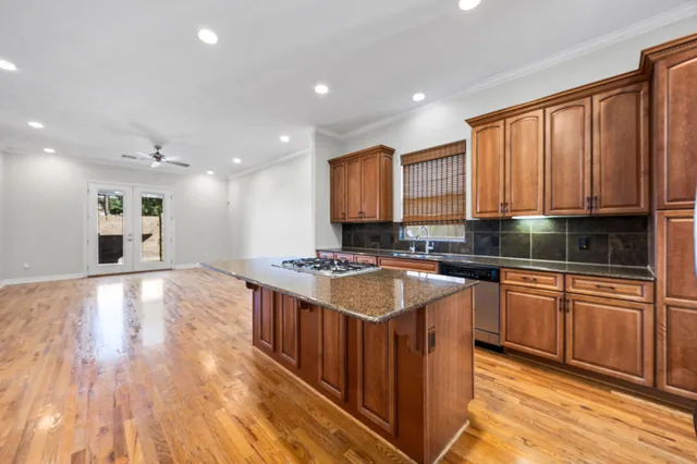 a kitchen with stainless steel appliances granite countertop a stove a sink dishwasher and a microwave oven with wooden floor